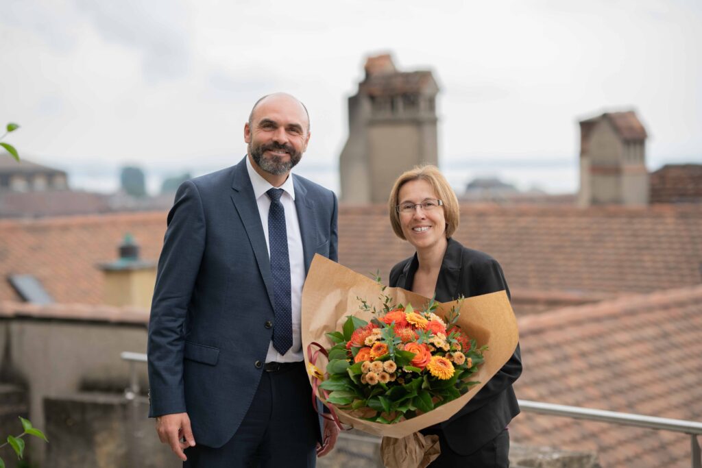 une femme avec un bouquet de fleurs et un homme rient à la caméra