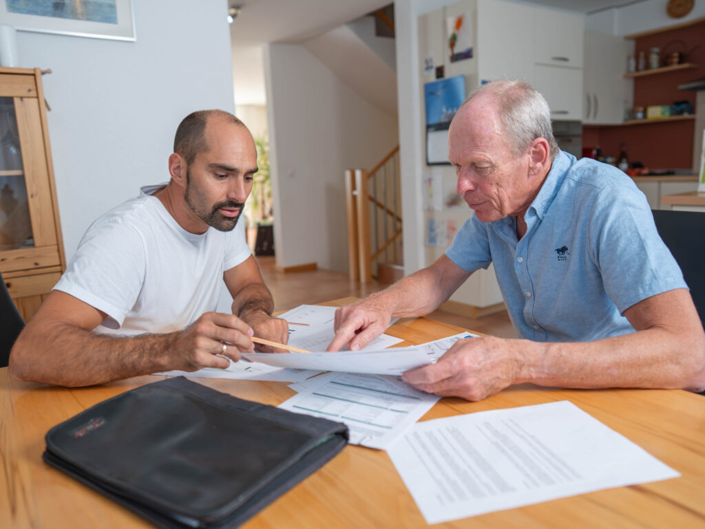 deux hommes sont assis à une table et examinent des documents